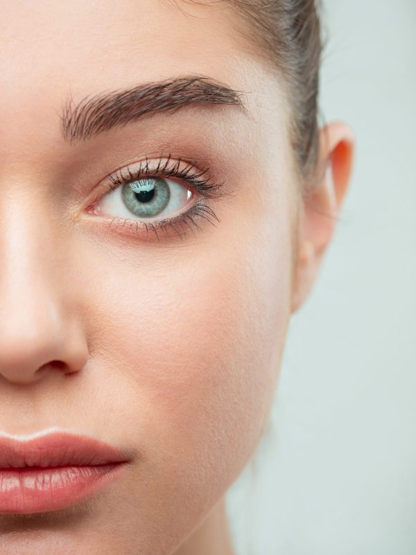 Beautiful Girl face. Perfect skin The beautiful female half face. The perfect and clean skin of face on gray
